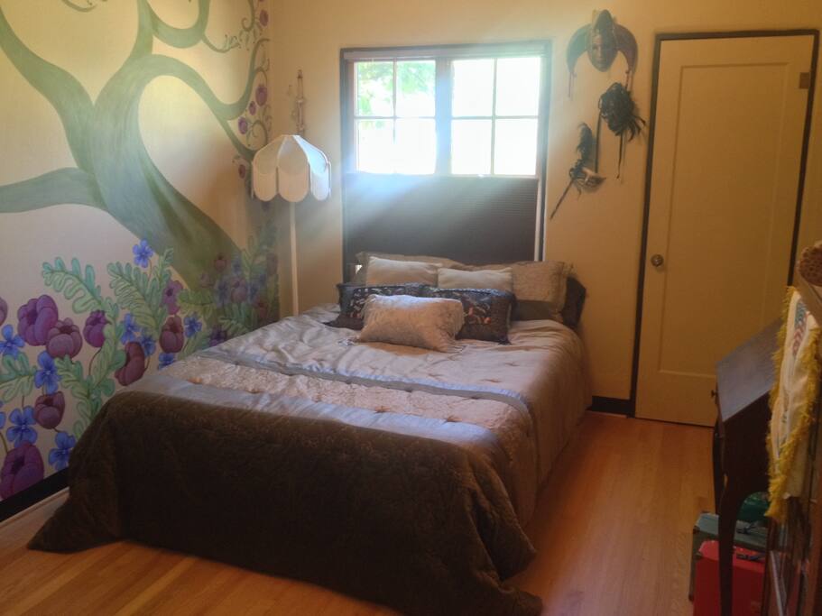 Guest bedroom with west light, Queen bed and mural on wall.