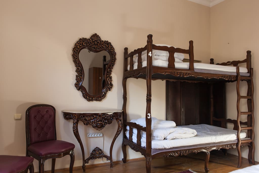 A bunk bed, mirror with a table, chairs