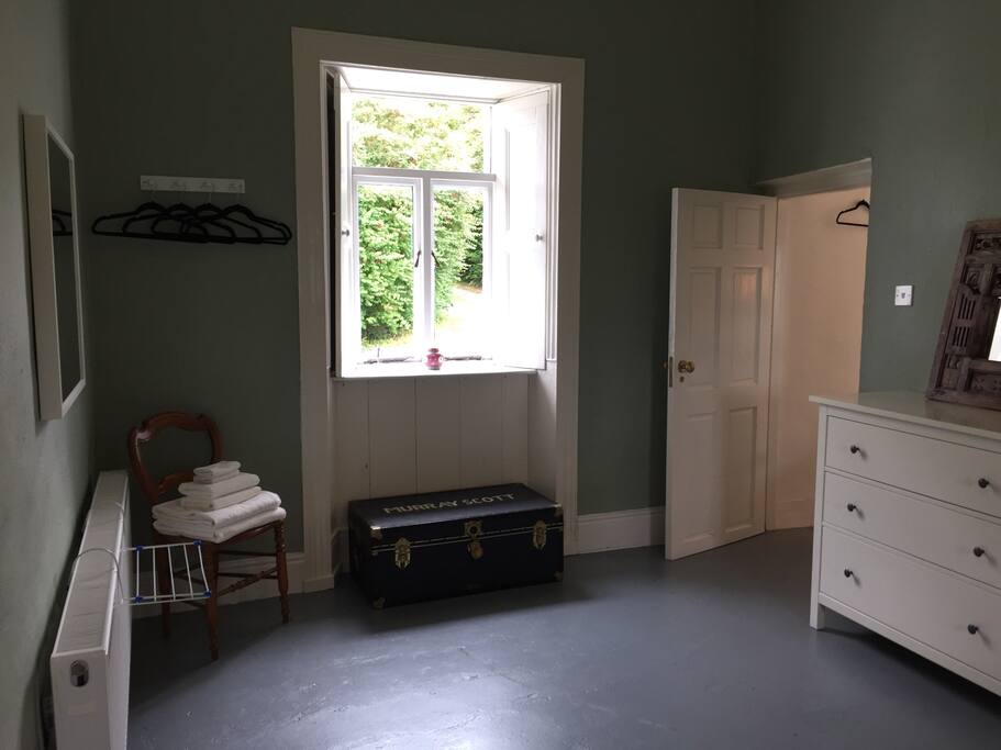 The other end of the bedroom looking out to the front of the house. Hanging space to the left, chest of drawers to the right.