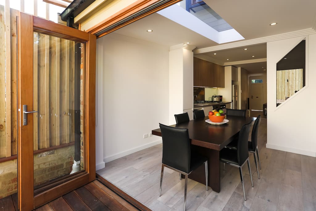 View from the outdoor deck area showcasing the dining area and kitchen area. Beautiful sliding doors can be opened up entirely to create an amazing open space.
