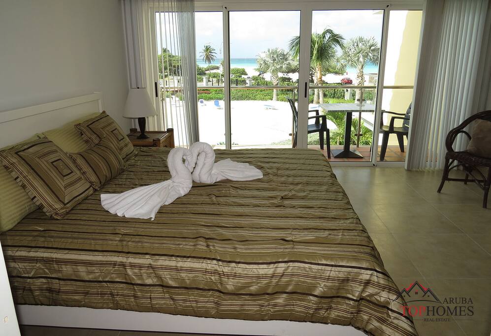 Main bedroom leading to second balcony with pool and beach view.