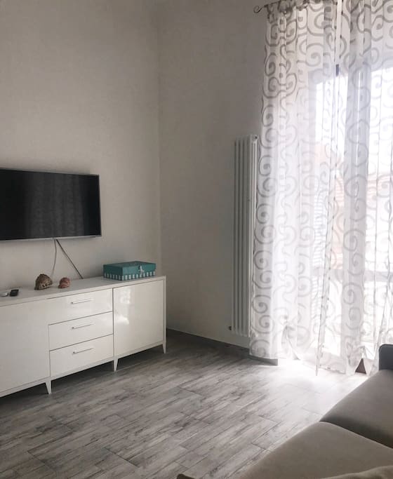 Altro lato della zona giorno con mobile + tv 43 pollici e accesso al balcone