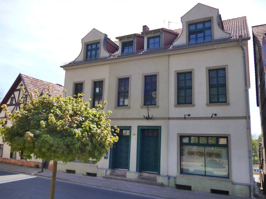 Das Haus beherbergte früher eine Handel für Schiffahrtszubehör und eine Schifferkneipe. Vor der Durchfahrt durch die Treppenschleuse oder dem Finowkanal lagen viele Schiffe am Ufer der Alten Oder auf Reede.