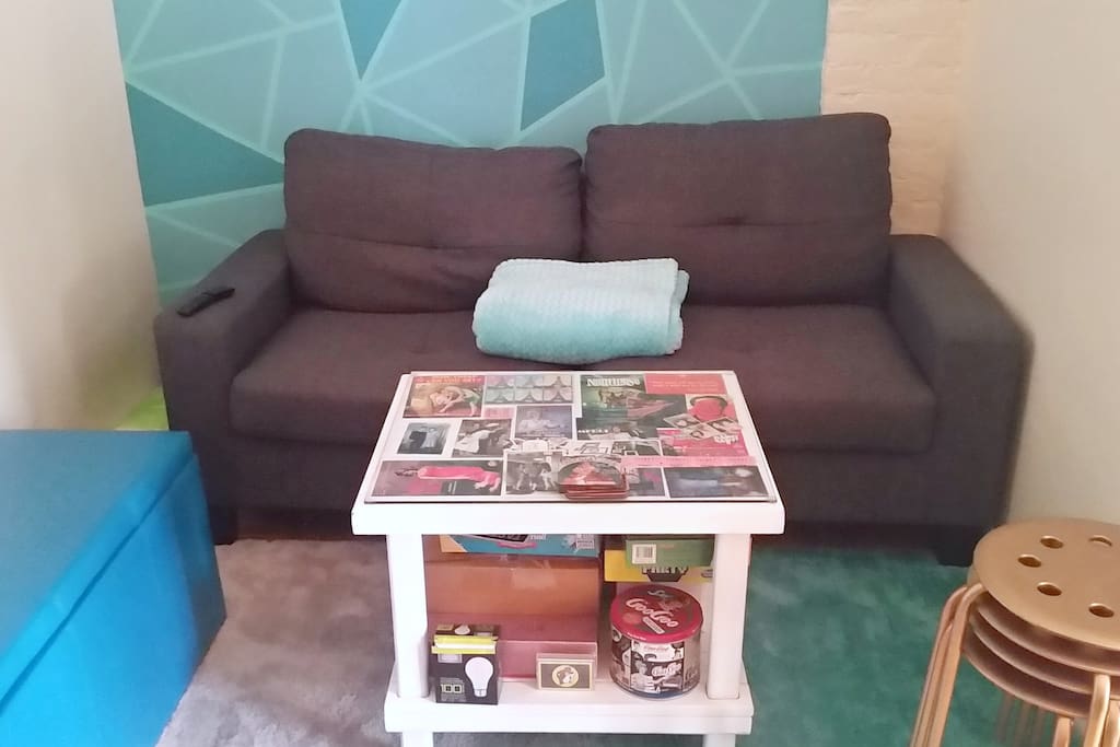 The living room is big enough for a 3-person couch and a 2-person ottoman, plus a coffee table and stools. The couch faces our bookshelf, which has a TV perched on top of it. Complete with a soft carpet and unique wall finish by moi.
