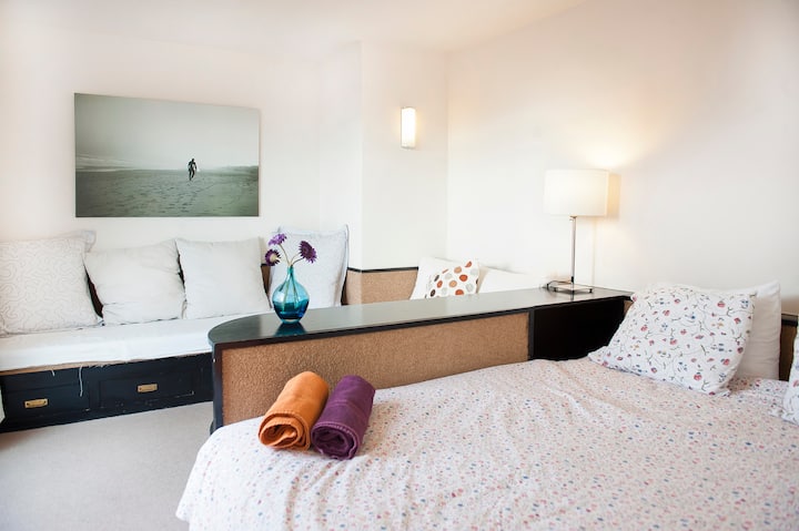 El salón está separado del dormitorio por una librería, lo que da al apartamento una sensación de apertura y luminosidad. Desde el dormitorio también hay acceso a la terraza, desde donde tenemos una hermosa vista de la Plaza Urquinaona, torres Mapfre y t