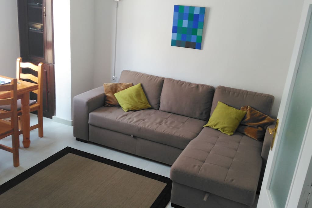 Living room with corner sofa/sofabed, extendible dining table with four chairs.