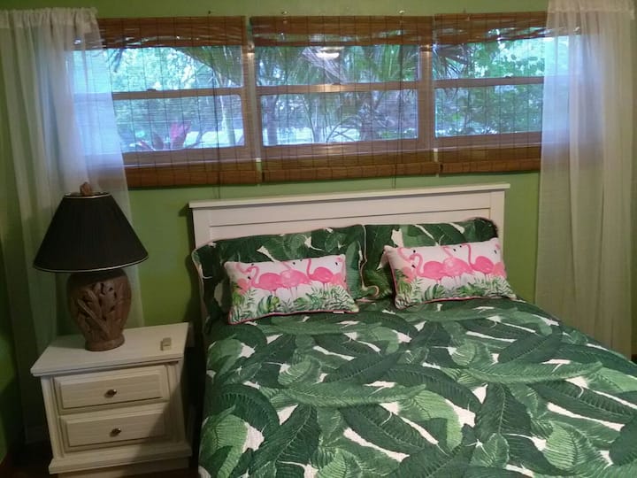Dormitorio tropical con cama tamaño queen.