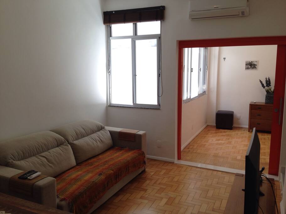 Sala com quarto de hóspedes ao fundo, ambos com bastante luz natural - living room with one of the bedrooms at the back, both with lots of sun light.