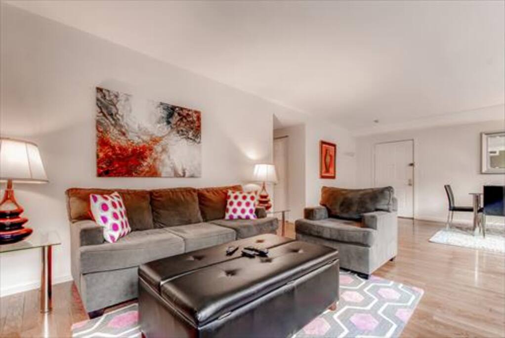 Comfortable living room with pullout sofa bed, club chair and many windows providing lovely natural light