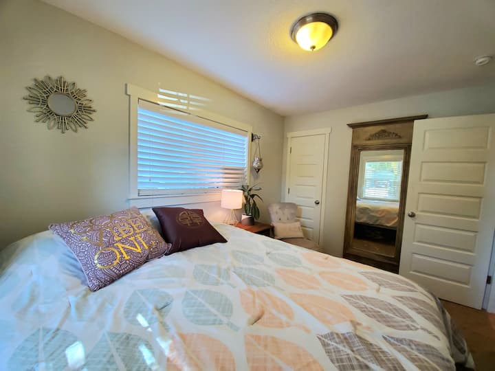 Spálňa č. 2 s veľkým zrkadlom, 2 oknami a množstvom vankúšov na manželskej posteli. Klimatizačná jednotka pri okne.