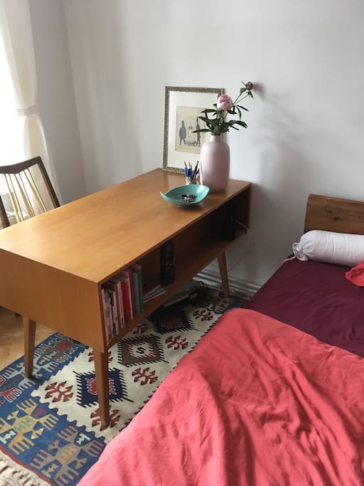 Desk between window and bed