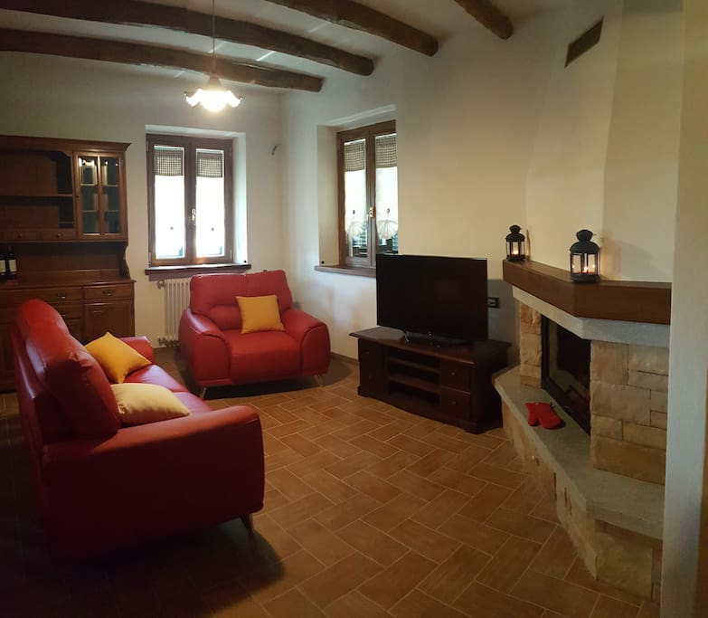 Salotto con divano, poltrona, tv hd e camino a legna con vetro - Living room with sofa, armchair, hd television and wood-burning fireplace with glass
