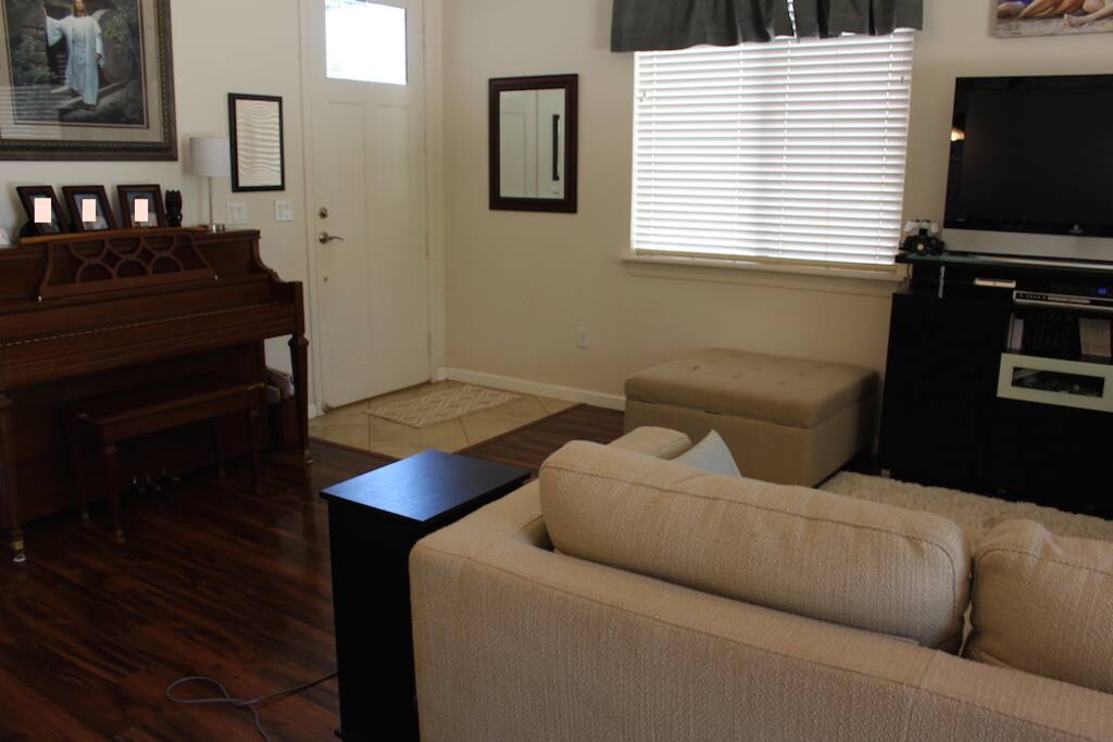 Spacious living area with sleeper sofa, area rug, desk, wifi, AppleTV, DVD player, flat screen TV, cable, piano, two ceiling fans and plenty of lighting
