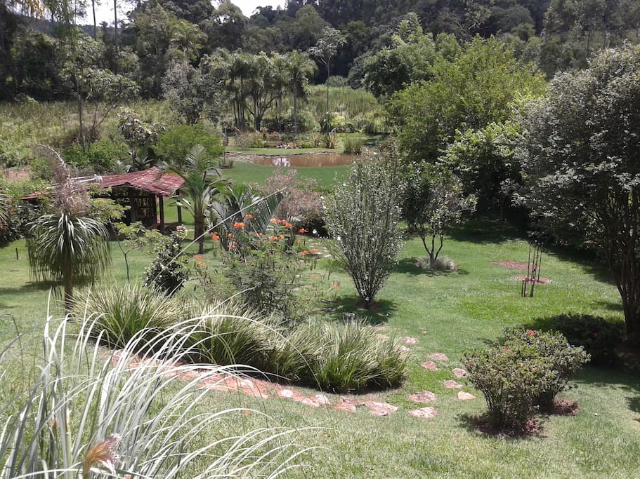 Jardim com flores e arvores frutíferas e lago ao fundo