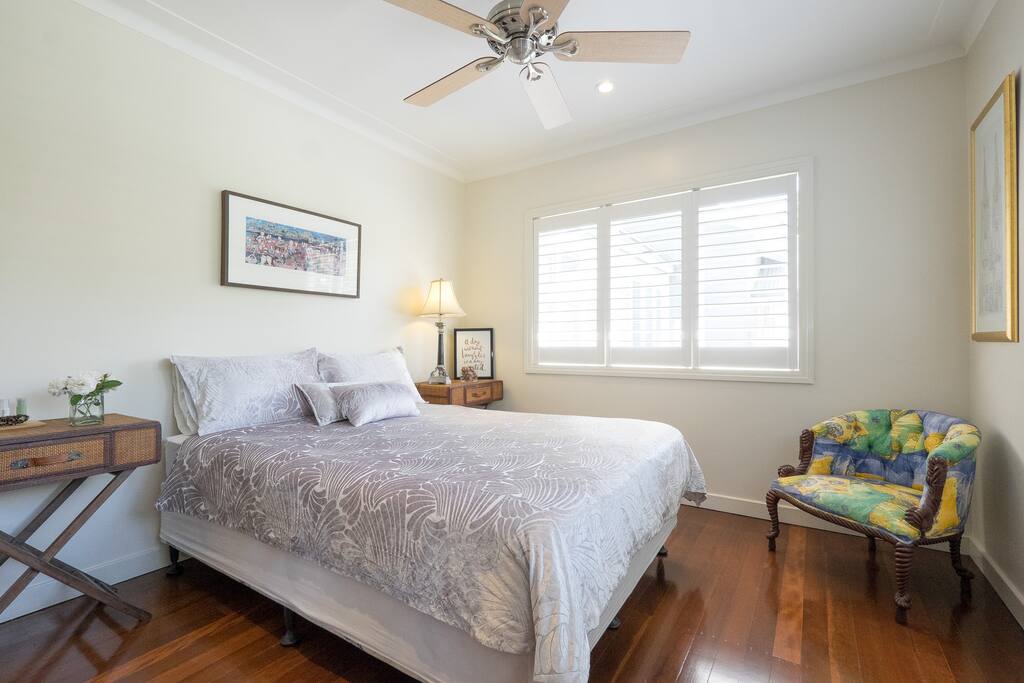 The bedroom is airy and bright, with two sets of windows that look out onto the front garden