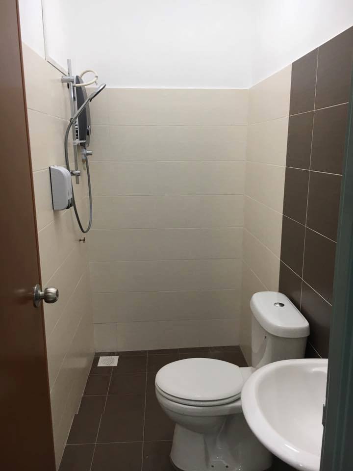 A modern bathroom features a shower area with a mounted water heater, a toilet, and a bidet. Neutral tiles in light shades provide a clean look, while the compact layout maximizes space efficiency.