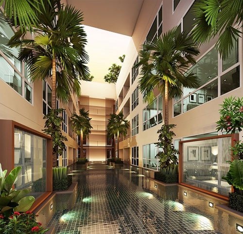 A serene hallway is lined with lush palm trees and vibrant plants, creating a refreshing atmosphere. The area features a tranquil water surface reflecting the surrounding greenery, complemented by large windows that allow natural light to fill the space.