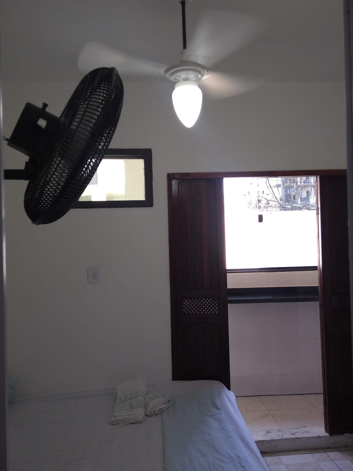 غرفة نوم بسرير مزدوج وسرير بطابقين ، مع جدار وسقف ومروحة سرير ومناشف للضيوف.