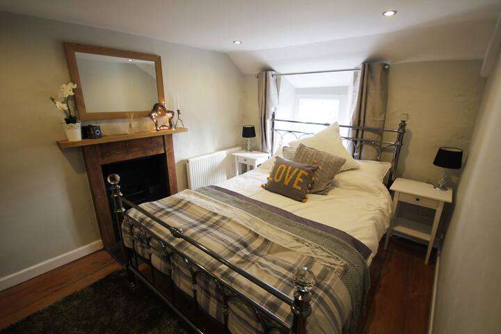 غرفة النوم الرئيسية بسرير بحجم كبير وفراش قطني مصري ورمي. هناك أيضاً راديو DAB.