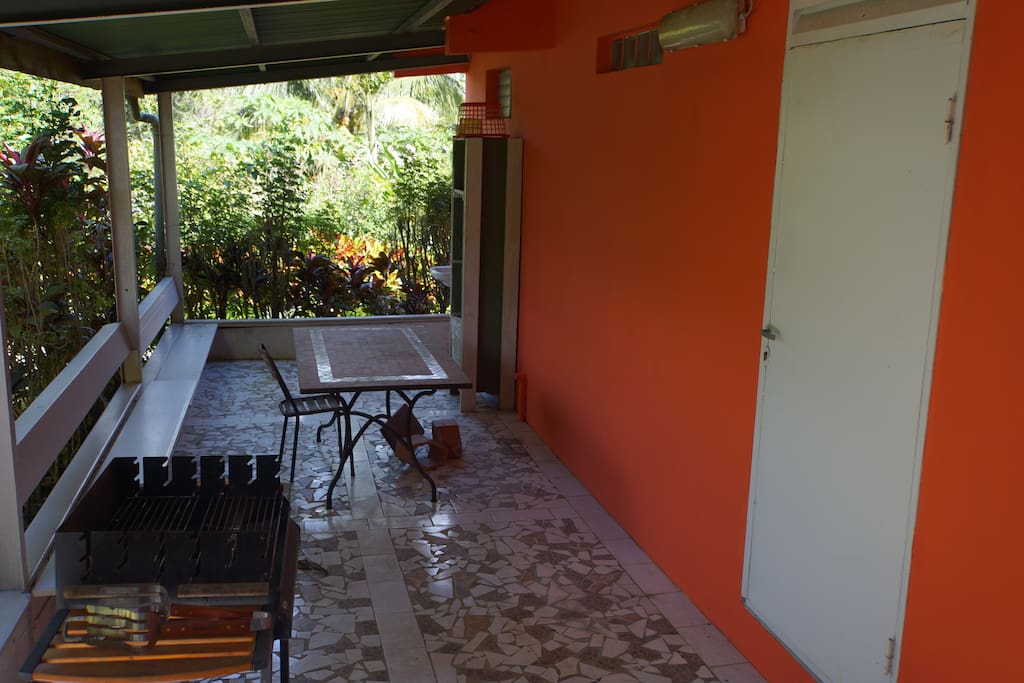 Terrasse arrière avec tables,chaises, bancs, barbecue.
