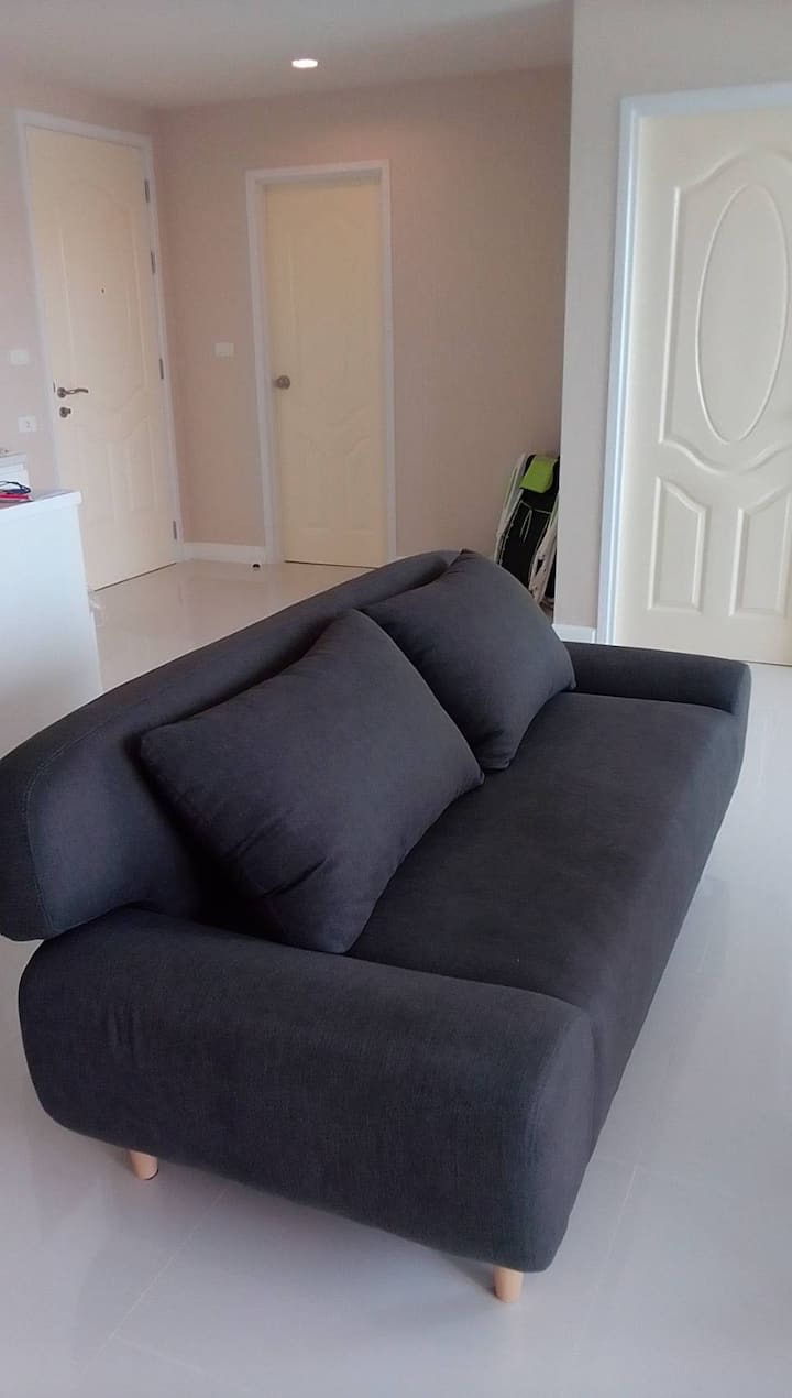 En hall mellan två sovrum och en bäddsoffa framför en TV.