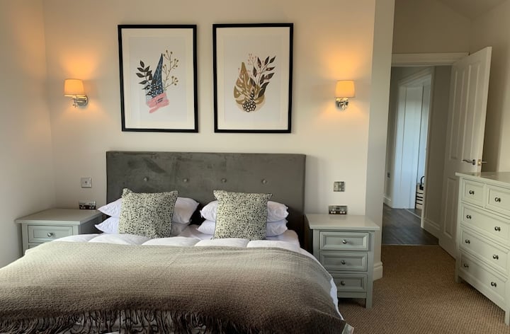 Dormitorio principal con cama tamaño king, TV y una gran sala húmeda.