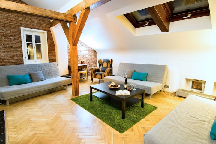A spacious living room with an original parquet floor. Equipped with three folding sofas, armchair, television and fan