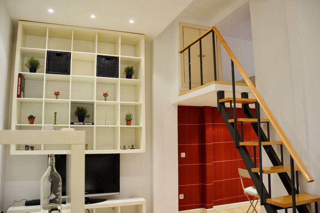 Salon con tv y escalera que sube al altillo.