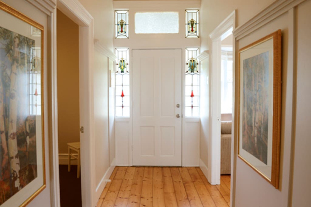 The welcoming, wide hallway features the original leadlight windows