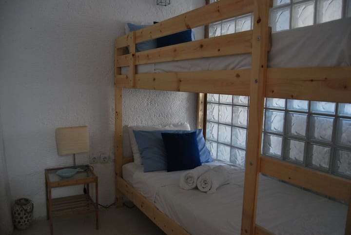 Dormitorio 4: pequeña habitación con literas y pared de ladrillo de vidrio contigua al dormitorio doble. Ideal para familias.
