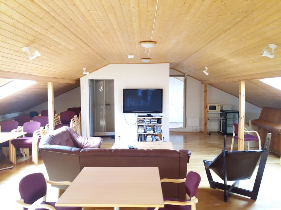 Living room/common area with tv, couches, kitchenette on the side. Lots of seating