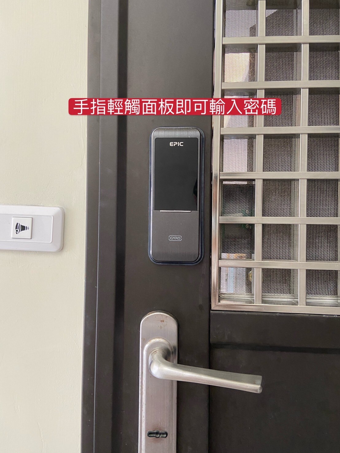 The image shows a sleek digital keypad lock mounted on a black door. The lock features a fingerprint scanner and a keypad for entry, ensuring secure access to the space. A door handle is visible alongside the lock, and a nearby light switch is also seen.