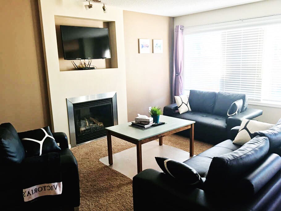 Beautiful open concept main level with kitchen, dining table, living space. Bright with natural light and features a Samsung Smart TV and a sofa set.