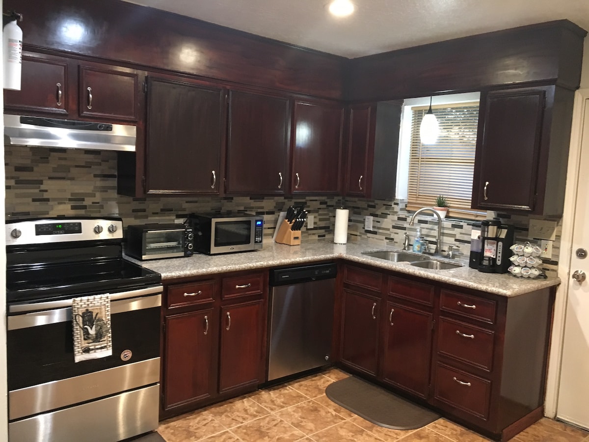 The kitchen features dark wood cabinetry and sleek granite countertops. Stainless steel appliances, including an oven, microwave, and dishwasher, are present. A stylish backsplash adds visual interest. Ample countertop space is available for meal preparation, with a sink positioned near a window for natural light.