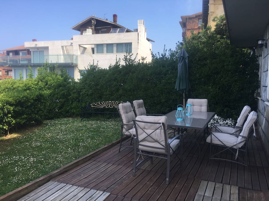 Jardín del apartamento con mesa de comedor , sombrilla y luz exterior.