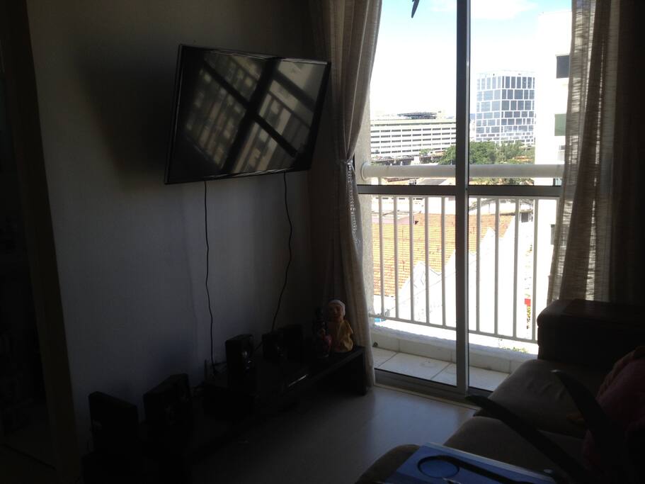 Sala de estar, com TV, home theater, sofá e sacada.