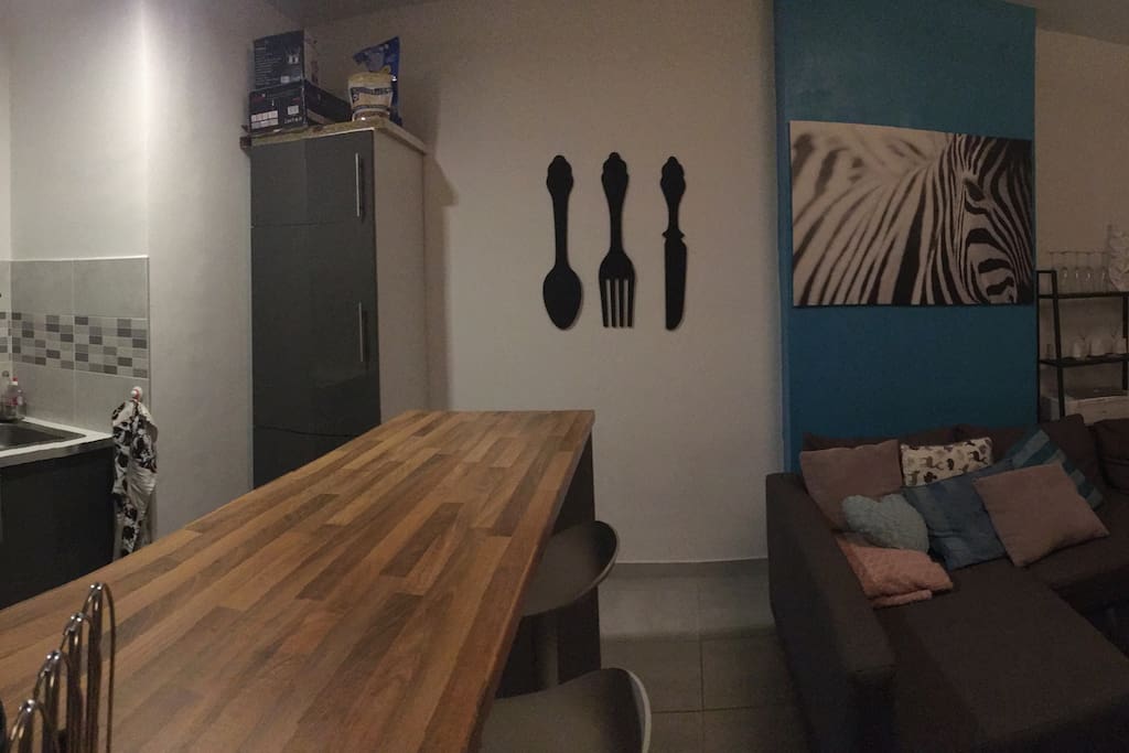Bar/table à mangé équipé de 4 chaises hautes. Grand frigo et congélateur, four, et équipements de cuisines.