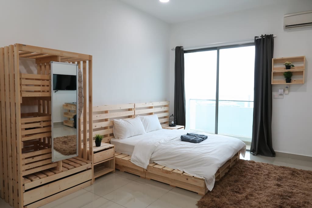 A spacious bedroom with 1 queen size bed and a wooden open wardrobe.