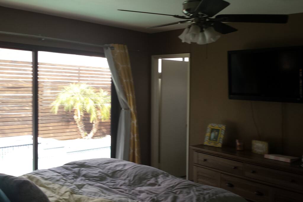 Private bathroom, dresser, and TV. Bedroom also has a ceiling fan.