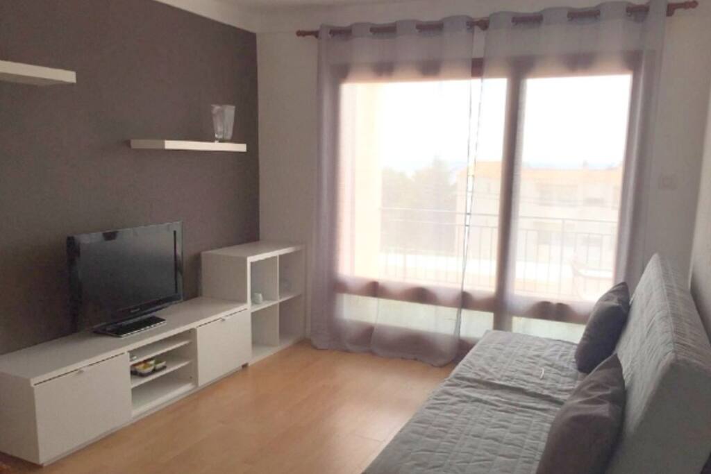 Comedor con TV pantalla plana, lámpara comedor, mesa comedor con sillas y sofá convertible en cama grande.