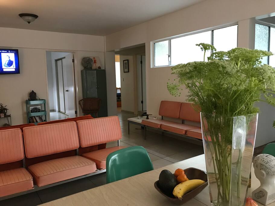 Vista del comedor hacia la sala con TV y entrada a cuartos.