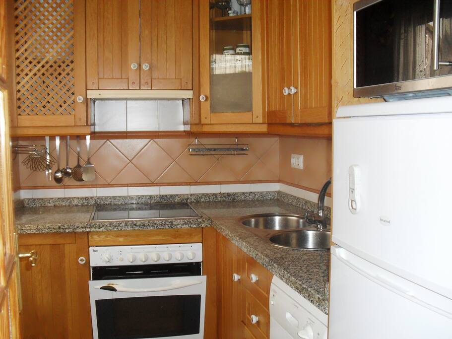 la cocina con ventana a la izquierda que da al patio consta de microondas horno, nevera y todo menaje para poder cocinar sin problemas