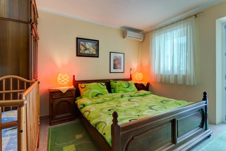 2号卧室毗邻床和空调，设有坐式婴儿床、衣柜和俯瞰大海的窗户。