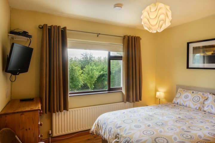Dormitorio 2 con cama tamaño king,  TV y vistas al jardín