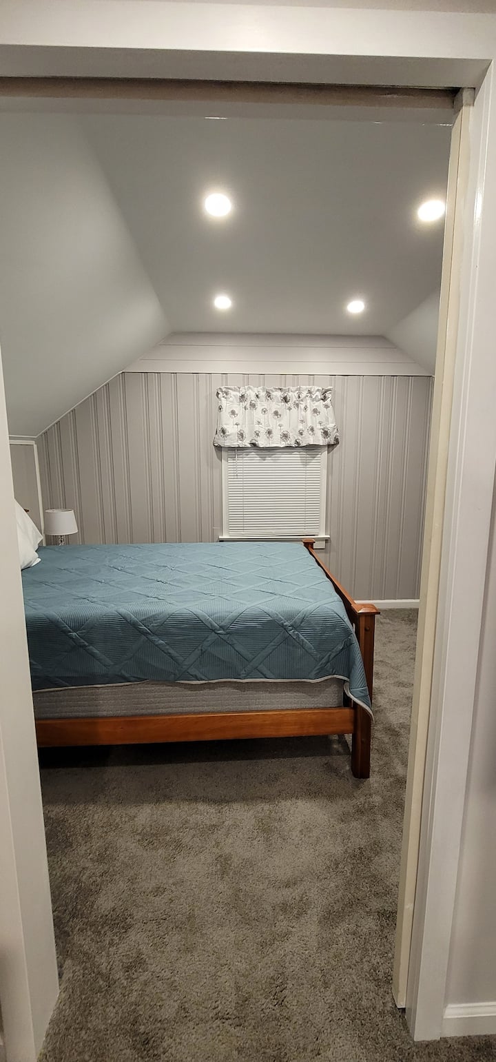 Our 2nd floor bedroom with a queen bed, new carpet, space-saving pocket door, soft-white and light gray walls & room-darkening blinds will provide its occupants comfort & space to rest.