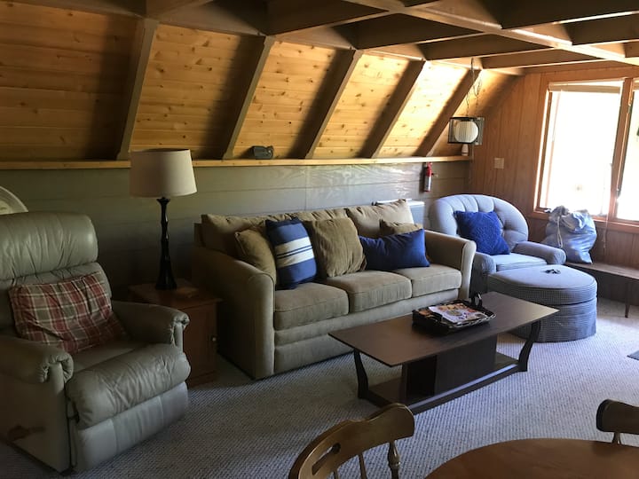 Main living space. Sleeper sofa, recliner, and chair with ottoman. Wall ac unit behind coach(right side).