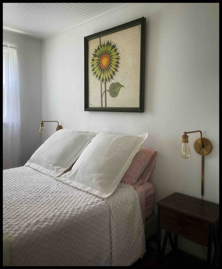 Chumba kikubwa cha kulala kina kitanda kamili na madirisha mawili makubwa ambayo yanaangalia ziwa kwa ajili ya kutazama jua.  