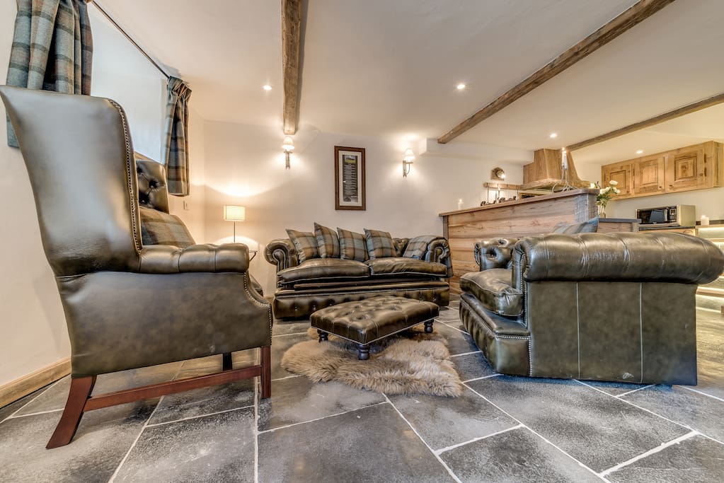 The living area features a leather sofa bed and 2 large, leather chairs.