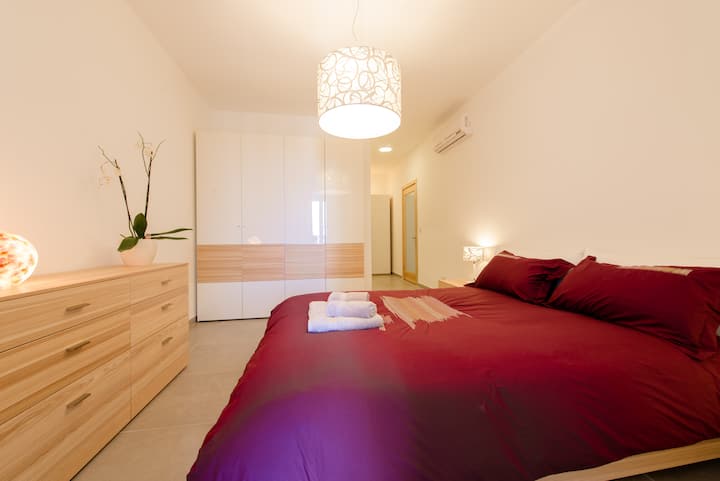 חדר שינה ראשי עם מיטה זוגית וחדר רחצה צמוד