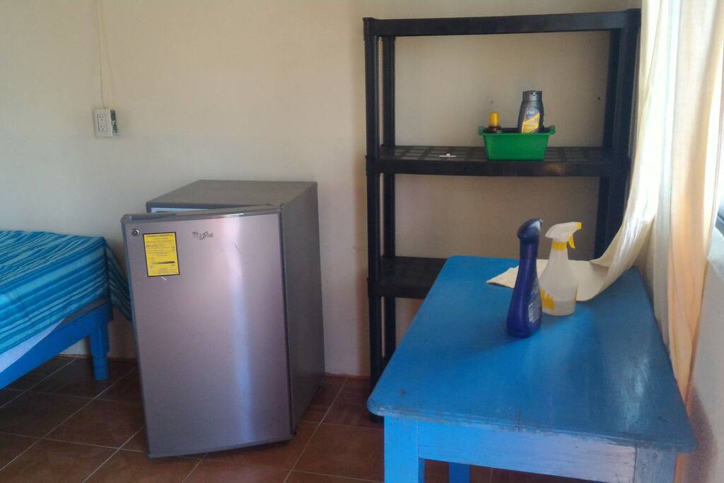 To the right of the door. Small fridge, shelves, table.